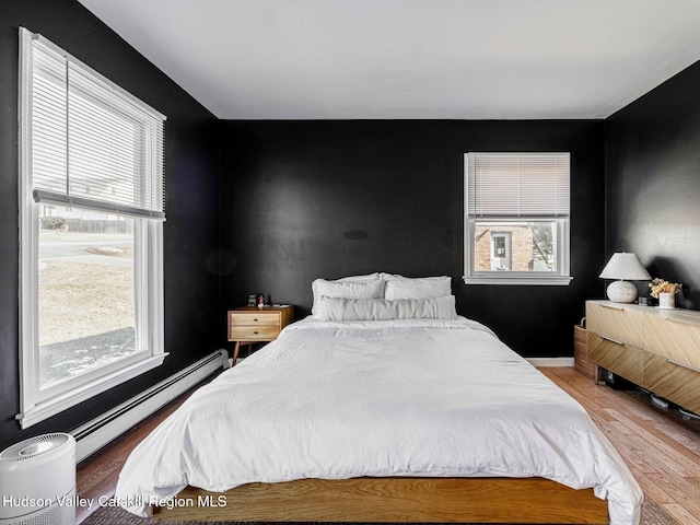 bedroom featuring a baseboard heating unit and wood finished floors