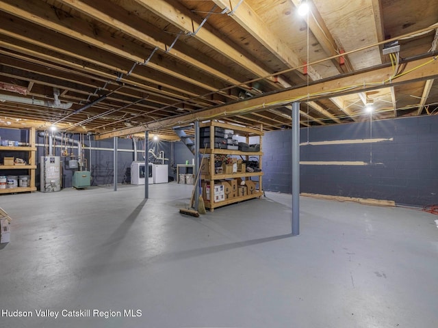 unfinished below grade area featuring separate washer and dryer, gas water heater, and concrete block wall