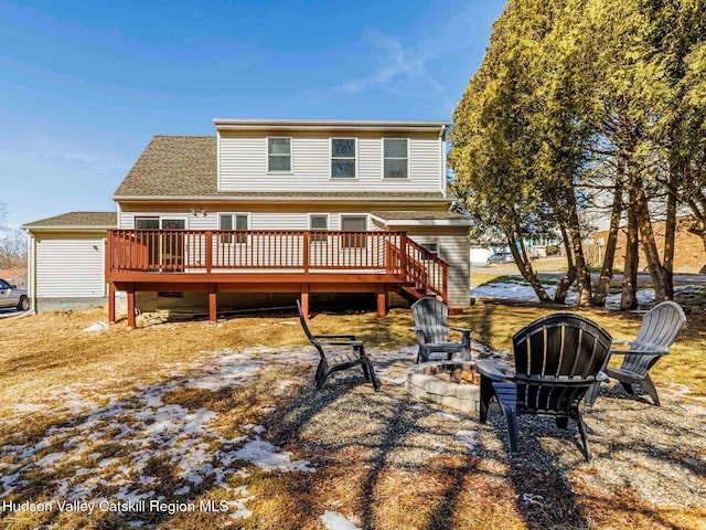 rear view of house with a shingled roof, a fire pit, and a wooden deck