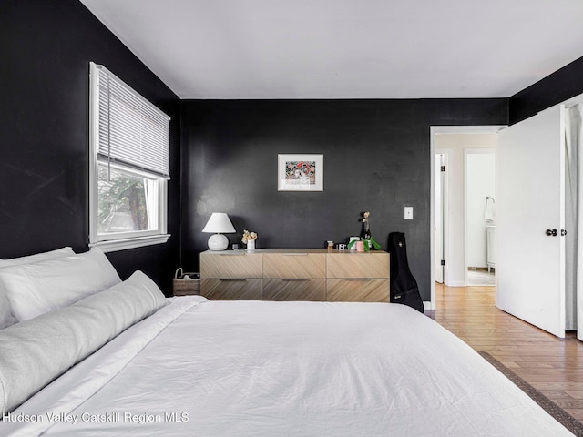 bedroom featuring an accent wall and wood finished floors