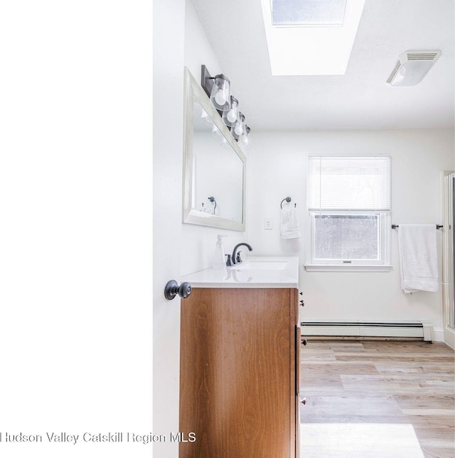 bathroom featuring visible vents, baseboard heating, wood finished floors, and vanity