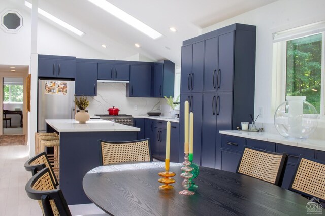 41 Snydertown Rd, Craryville, NY 12521 - kitchen with blue cabinets, decorative backsplash, vaulted ceiling, a breakfast bar, and light countertops