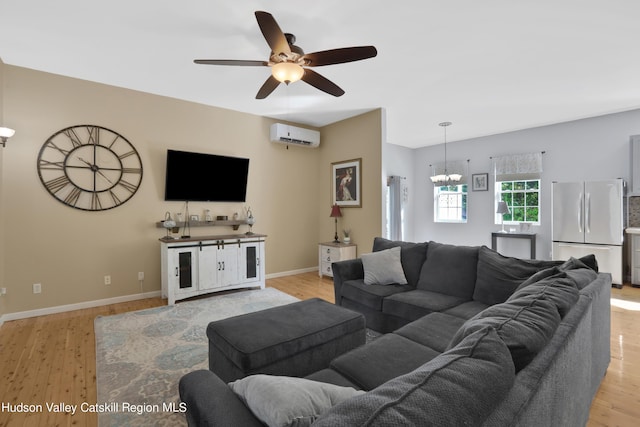 living room with ceiling fan with notable chandelier, light wood-type flooring, and a wall unit AC