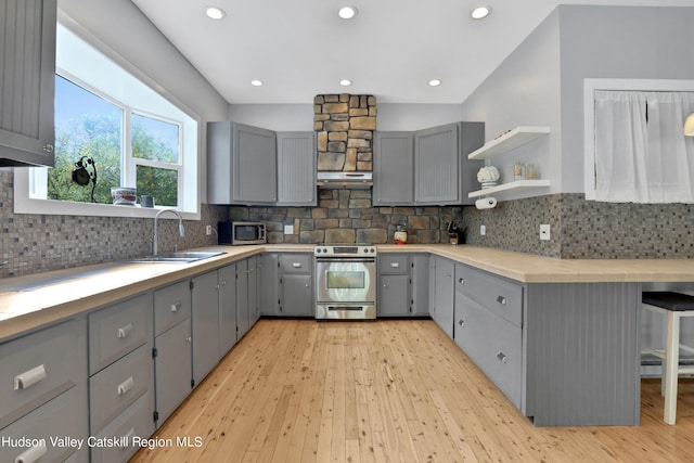 kitchen with sink, stainless steel appliances, gray cabinets, decorative backsplash, and light wood-type flooring