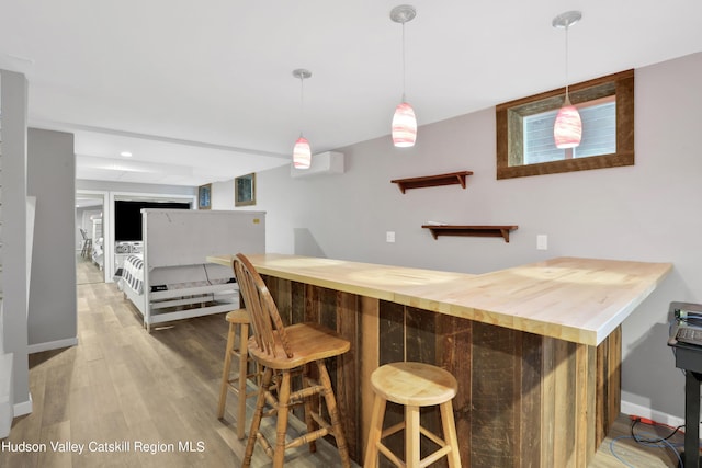 bar with hardwood / wood-style floors, wood counters, hanging light fixtures, and a wall mounted AC