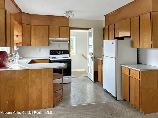 kitchen with kitchen peninsula, sink, white refrigerator, a kitchen bar, and electric range oven