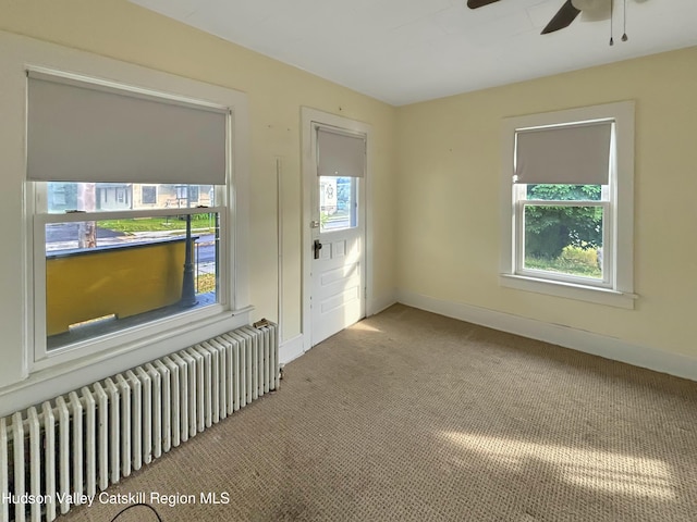 unfurnished room with ceiling fan, plenty of natural light, radiator, and carpet flooring