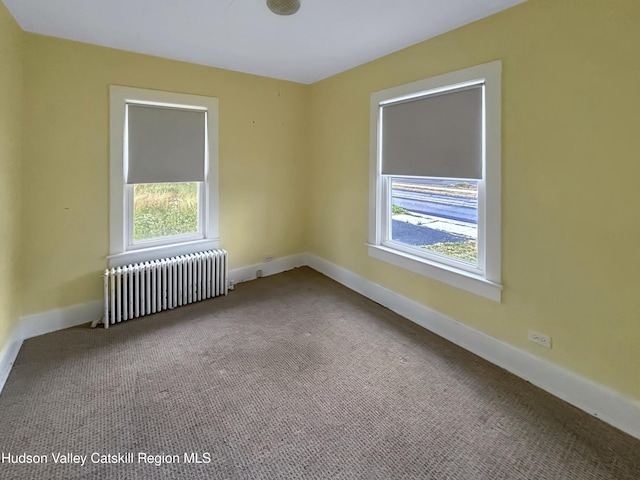 spare room featuring carpet flooring, radiator, and a healthy amount of sunlight