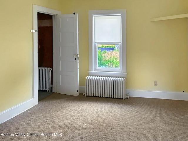 spare room featuring carpet flooring and radiator