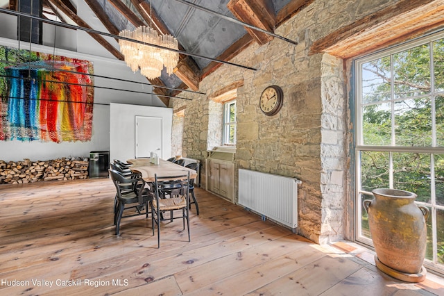 dining area with beam ceiling, an inviting chandelier, high vaulted ceiling, and radiator