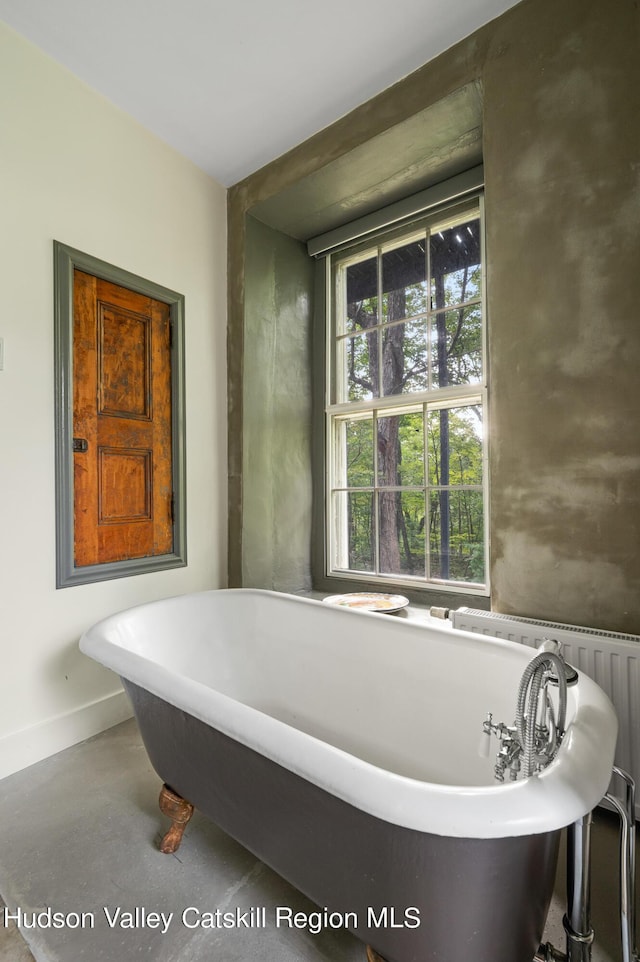 bathroom featuring a bath and concrete flooring