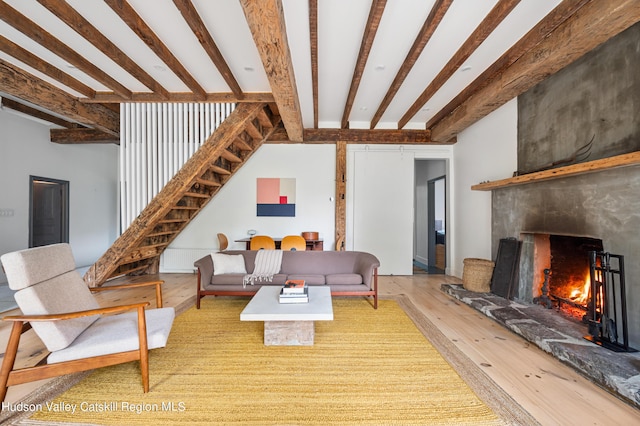 living room with a large fireplace, beamed ceiling, and wood-type flooring