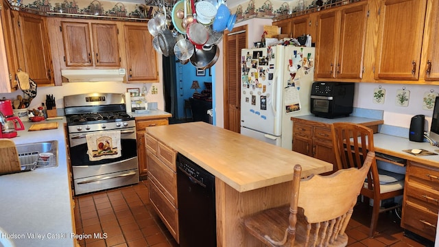 kitchen featuring under cabinet range hood, freestanding refrigerator, a center island, dishwasher, and stainless steel range with gas stovetop