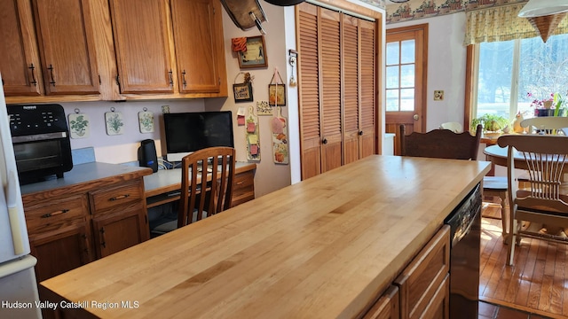 kitchen featuring butcher block counters, built in study area, and brown cabinets