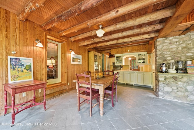 tiled dining area featuring wood walls, beamed ceiling, and wood ceiling