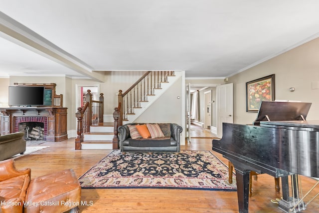 living room with a fireplace, ornamental molding, and hardwood / wood-style flooring