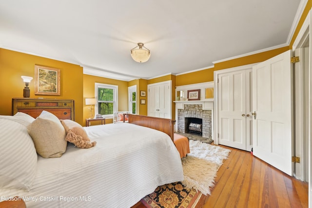 bedroom with light wood-type flooring, crown molding, and a brick fireplace