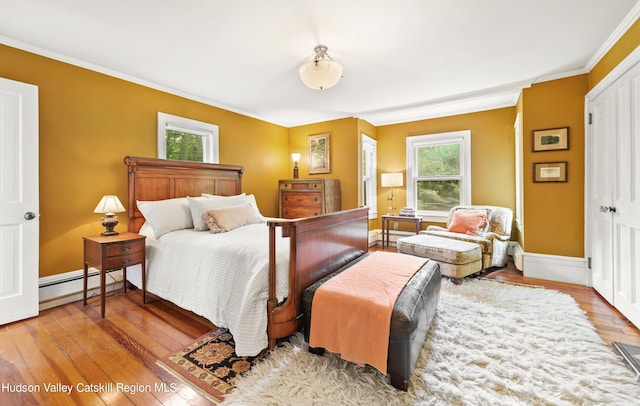 bedroom with baseboard heating, ornamental molding, and hardwood / wood-style flooring