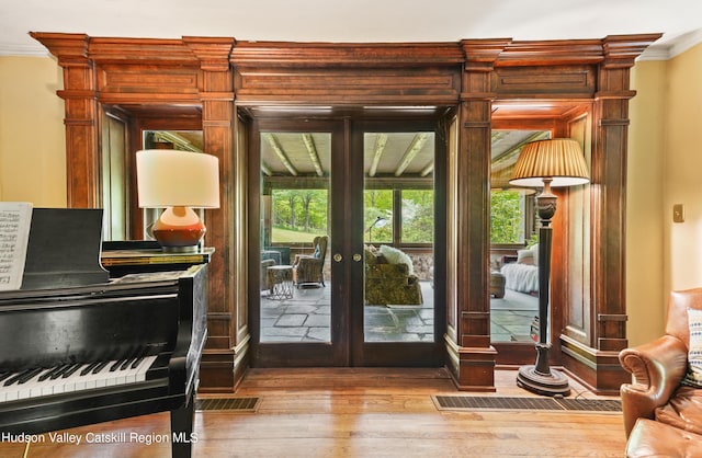 entryway featuring french doors, light hardwood / wood-style flooring, and crown molding