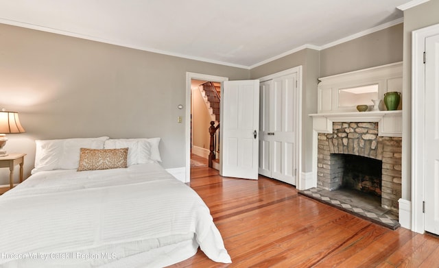 bedroom featuring a fireplace, wood-type flooring, and crown molding