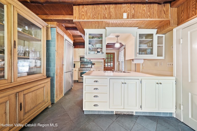 kitchen with white cabinets, hanging light fixtures, sink, appliances with stainless steel finishes, and beam ceiling