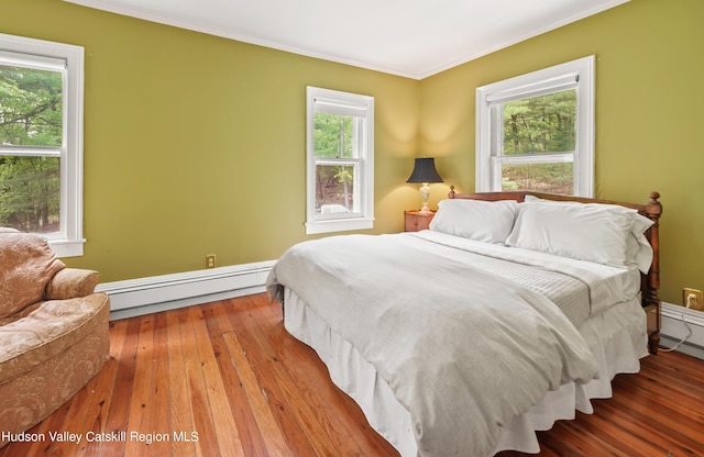 bedroom with crown molding, wood-type flooring, and baseboard heating