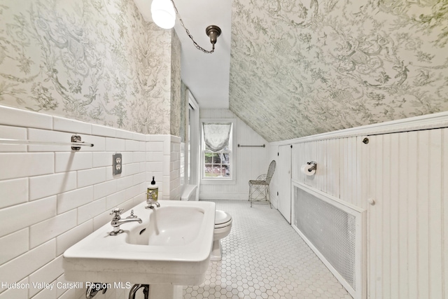 bathroom with tile patterned floors, wood walls, lofted ceiling, and toilet