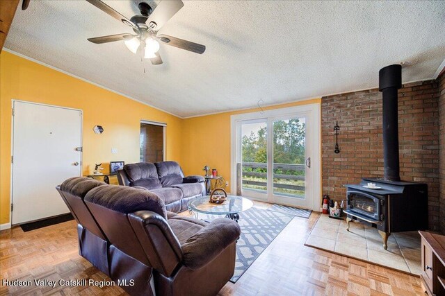 living room with a wood stove, light parquet floors, vaulted ceiling, ceiling fan, and a textured ceiling