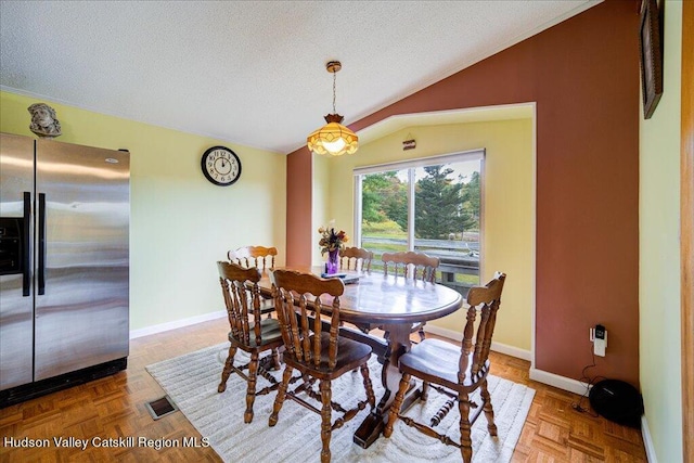 dining area featuring a textured ceiling, parquet floors, and vaulted ceiling