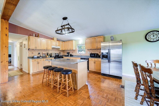 kitchen with black appliances, a kitchen breakfast bar, vaulted ceiling, a kitchen island, and light parquet flooring