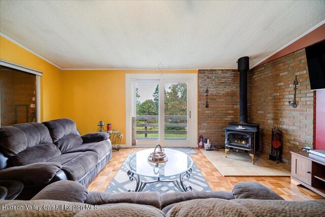 living room with a wood stove, light parquet floors, crown molding, a textured ceiling, and brick wall