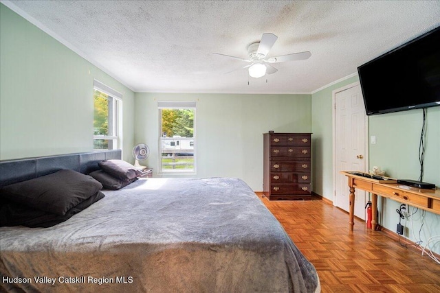 bedroom with ceiling fan, parquet floors, a textured ceiling, and ornamental molding