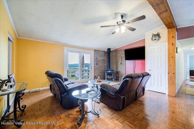 living room featuring a textured ceiling, ceiling fan, crown molding, a wood stove, and lofted ceiling