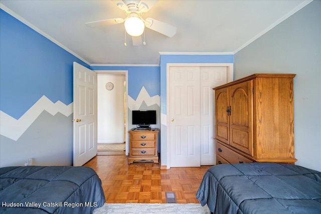 bedroom featuring ceiling fan, parquet flooring, ornamental molding, and a closet