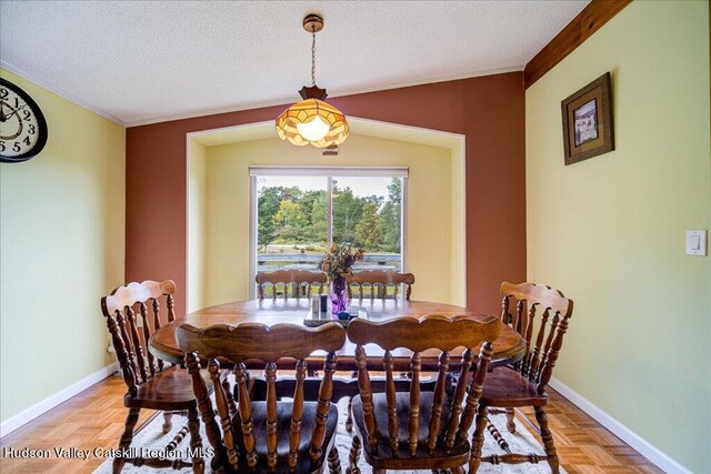 dining area featuring light parquet flooring, a textured ceiling, and ornamental molding