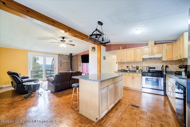 kitchen featuring a center island, a wood stove, lofted ceiling with beams, gas stove, and a kitchen bar