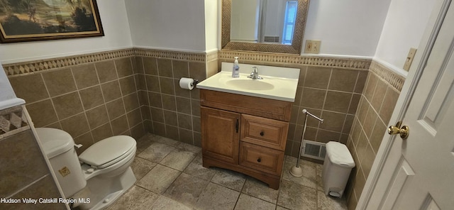 bathroom with vanity, tile walls, and toilet