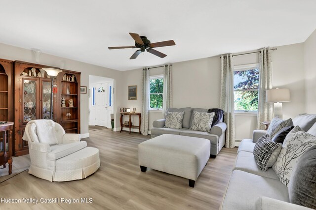 living room featuring ceiling fan, baseboard heating, a wealth of natural light, and light hardwood / wood-style flooring