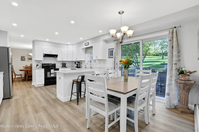 dining area featuring a chandelier, light hardwood / wood-style floors, a baseboard heating unit, and sink