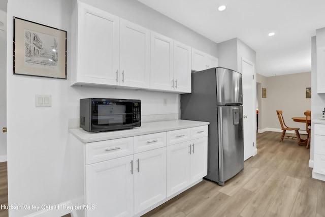 kitchen featuring light wood-type flooring, white cabinetry, and stainless steel refrigerator