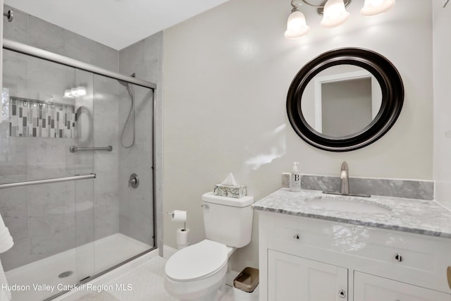 bathroom featuring vanity, toilet, and a shower with shower door