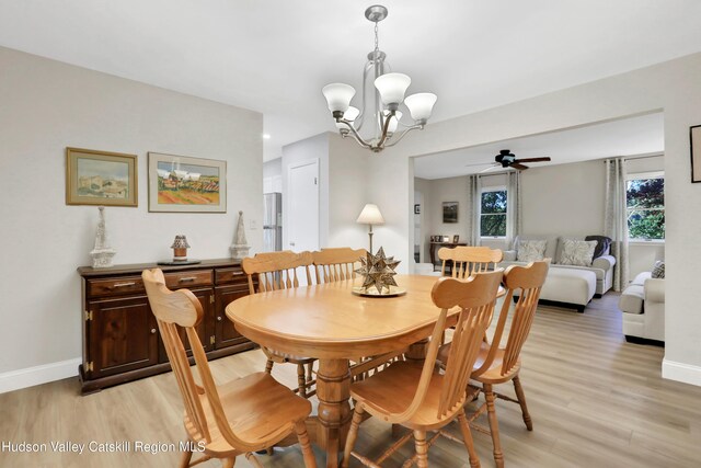 dining room with ceiling fan with notable chandelier and light wood-type flooring