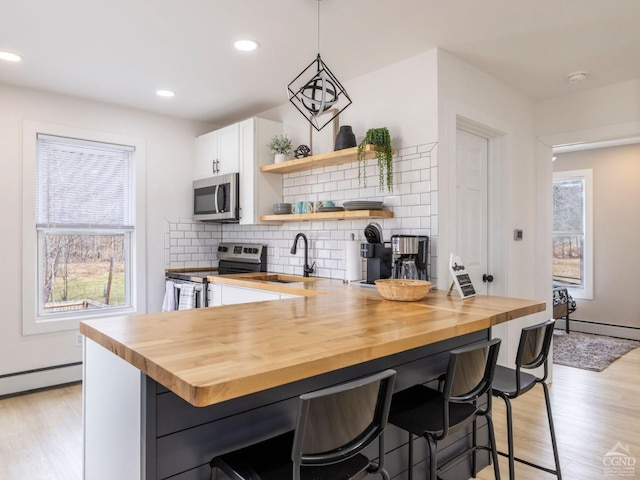 7614 Main St, Hunter, NY 12444 - kitchen featuring appliances with stainless steel finishes, a sink, wood counters, a kitchen breakfast bar, and light wood finished floors