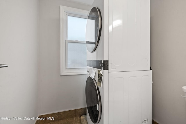clothes washing area featuring stacked washer / dryer and baseboards