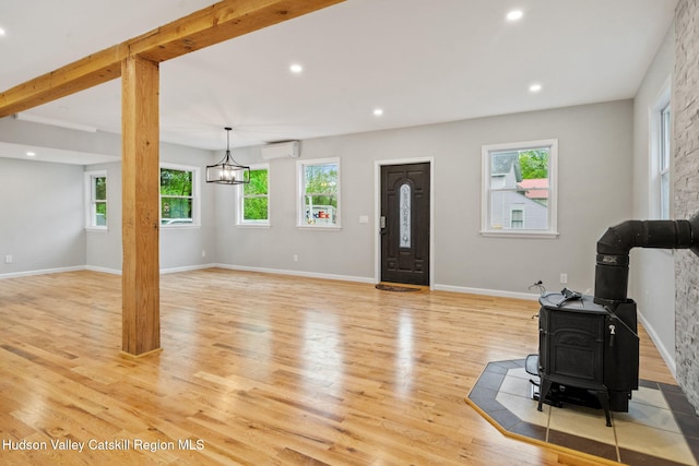 living room with a wood stove, a wall unit AC, light wood finished floors, recessed lighting, and baseboards