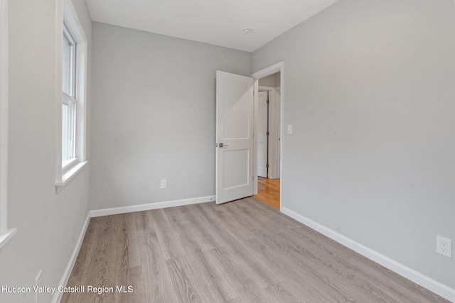 unfurnished room with light wood-style flooring and baseboards