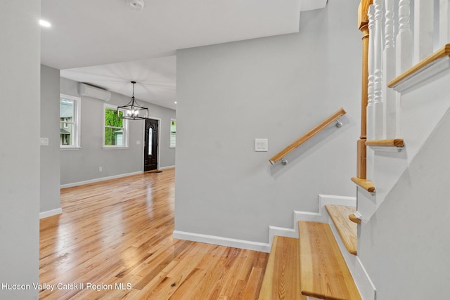 stairs featuring wood finished floors, a wall mounted air conditioner, and baseboards