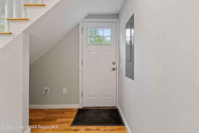 foyer entrance featuring wood finished floors, lofted ceiling, and baseboards