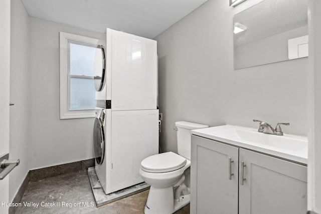 bathroom with stacked washer / drying machine, toilet, vanity, and baseboards