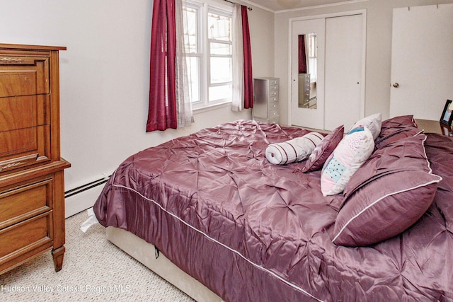 bedroom with ornamental molding, baseboard heating, carpet, and a closet